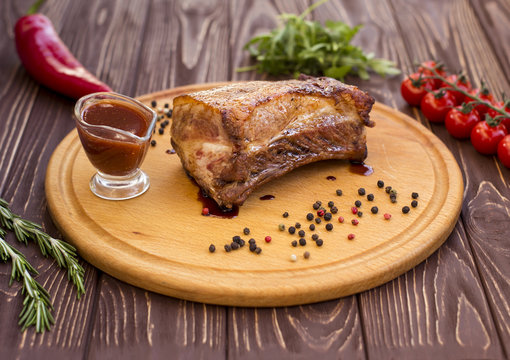 Grilled pork cooked on barbecue, closeup on dark wooden table background. Fresh juicy roasted red meat