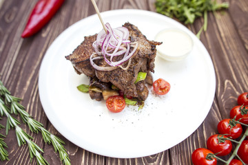 Meat steak with vegetables and cream sauce. On a wooden background