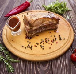 Grilled pork steaks and rosemary on wood background.