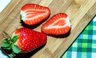 Strawberries with sliced half and leaves isolated on wooden table