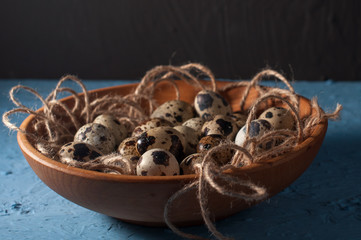 quail eggs in wooden bowl isolated on blue background close up
