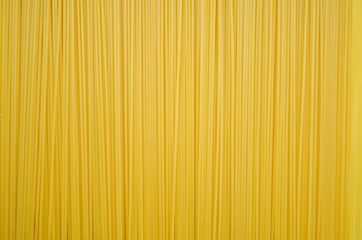 Uncooked pasta spaghetti macaroni yellow background