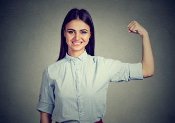 Young happy woman flexing muscles showing strength