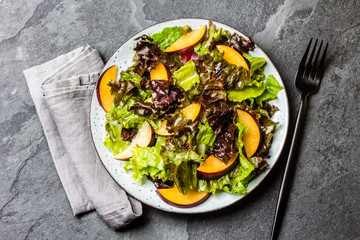Vegetarian vegan lettuce salad with plums on black slate background. Top view