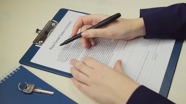 Woman signing real estate sales contract