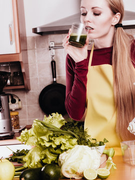 Woman in kitchen holding vegetable smoothie juice