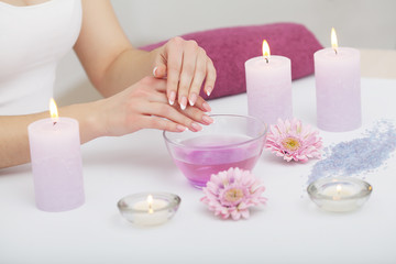 Obraz na płótnie Canvas Spa Beauty Salon. Closeup Of Female Hands With Perfect Natural Fingernails Soaking In Hand Bath Before Manicure. Woman Washing Perfect Nails In Transparent Bowl Of Water. Nail Care. High Resolution