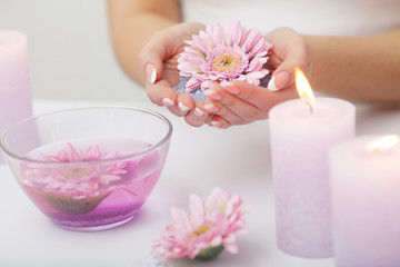 Fototapeta na wymiar Spa Procedure. Woman In Beauty Salon Holding Fingers In Aroma Bath For Hands. Closeup Of Female Nails Soaking In Bowl Of Water With Floating Pink Flower Petals. Skin Care. High Resolution