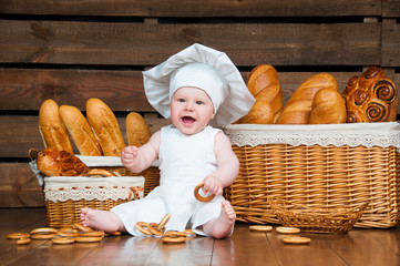 Child cooks a croissant in the background of baskets with rolls and bread.