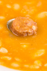 Closeup macro of cooked beans with sausage in the spoon