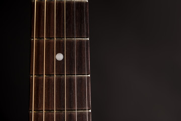 Part of the neck, wooden acoustic guitar, on the left side of the frame, on a black isolated background