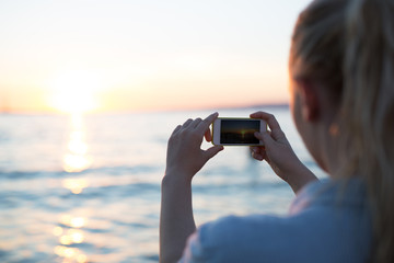 Woman using phone on the beach. Summer time.