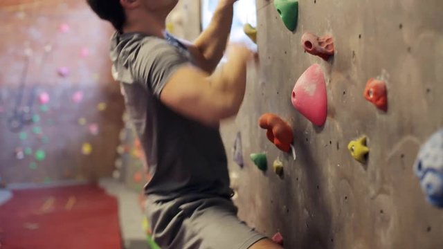 young man exercising at indoor climbing gym wall
