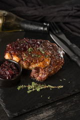 Steak and wine on black stone plate. Black table background with copy text area for menu design. Vertical top view.