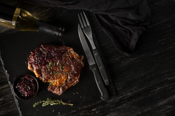 Steak and beer craft bottle with herbs on black stone plate. Black table background with copy text area for menu design. Horizontal top view.