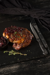 Grilled meat on black stone plate. Black table background with copy text area for menu design. Horizontal top view.