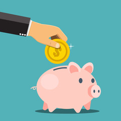 Businessman hand putting a coin into a piggy bank. Saving and investing money concept. 