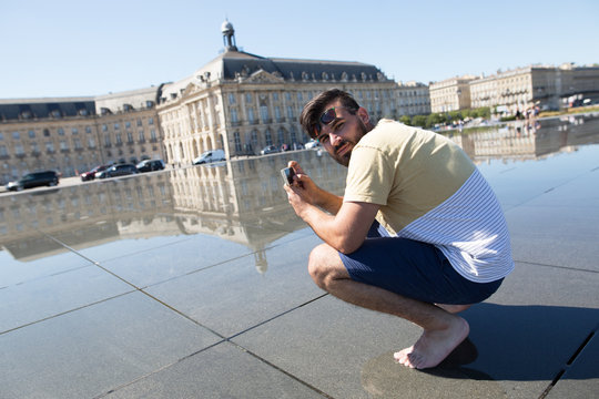 Man taking photos on his phone on main square in Bordeaux in France