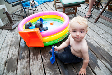 11 month old baby boy playing next to kiddie pool on deck