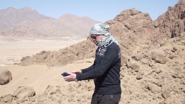 Man in the desert touching his smart phone