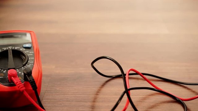 Measurement of voltage in electrical socket extension cord with multimeter on wooden floor background 4K ProRes HQ codec