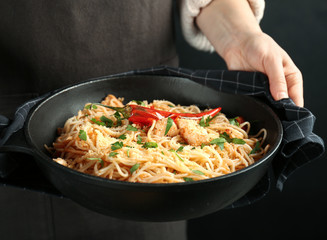 Woman holding frying pan with tasty chicken spaghetti, closeup