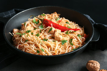 Frying pan with delicious chicken spaghetti on table