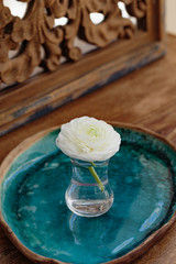 white ranunculus in glass on ceramic tray