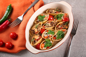 Baking dish with stuffed pasta on table