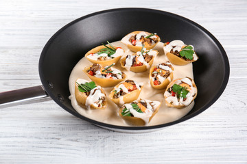 Pan with stuffed pasta on wooden table