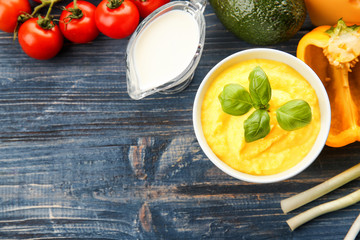 Bowl with cheese sauce and different products on wooden background