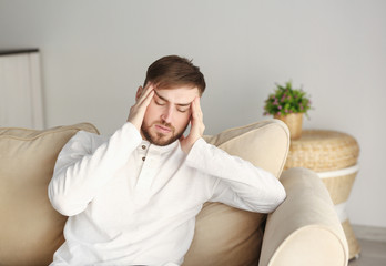 Fototapeta premium Young man suffering from headache at home