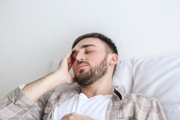 Fototapeta premium Young man with headache lying on bed