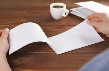 Female hands holding blank brochure on wooden background