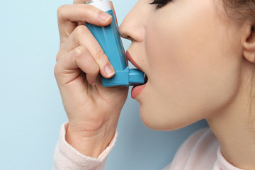 Young woman using asthma inhaler, closeup