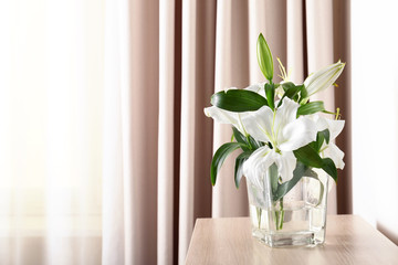 Beautiful white lilies in vase on table