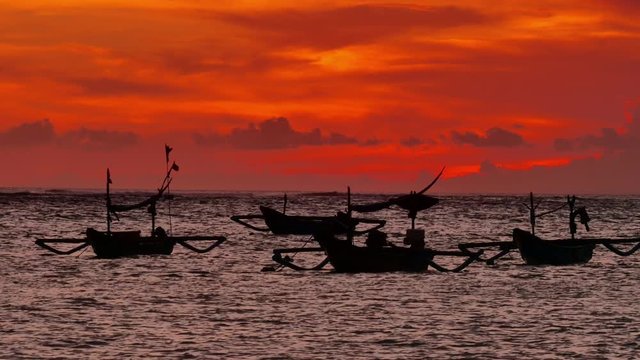 Black silhouettes of fishing boats at beautiful orange sunset in bali island