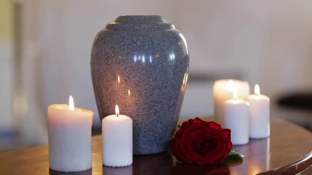 funerary urn and candles on table burning indoors