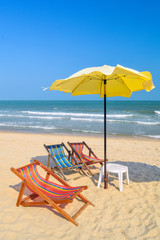 Pair of sun loungers and a beach umbrella on a deserted beach; perfect vacation concept