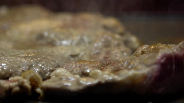 Slow motion cheff is cooking a Steak in hot Griddle of a kichen. Slowmo T-bone steak is low fat healthy living meal choice-Dan