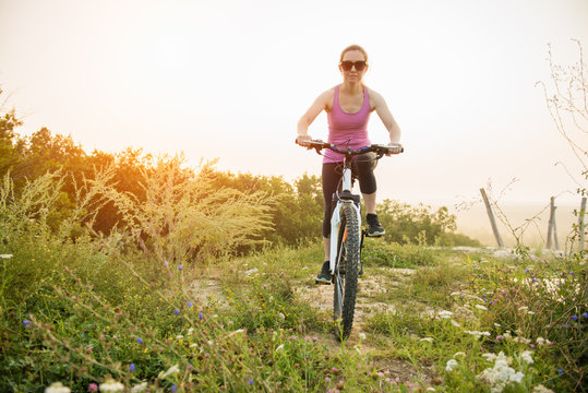 Girl on mountain bike rides on the trail on a beautiful sunrise