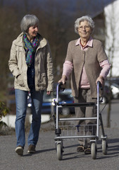 Seniorin mit Rollator wird von ihrer Tochter begleitet