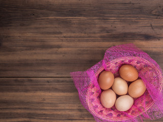 Easter eggs in the basket on the background of wooden table from the old boards, top view. Background with copy-space in rustic style for advertising or Easter greetings