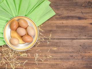 Rural eco background with brown chicken eggs, a piece of burlap and straw on the background of old wooden planks. The view from the top. Creative background for Easter cards or menu