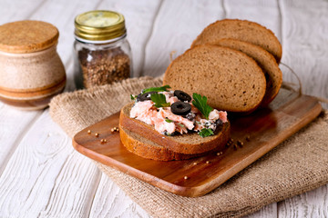 Smoked salmon and soft cheese spread, mousse, pate on a bread with olives and parsley