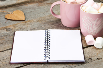 Pink cup with marshmallow and notebook