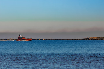 Red pilot ship moving past the breakwater dam in Riga, Europe