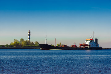 Black cargo oil tanker entering the port of Riga at sunny day