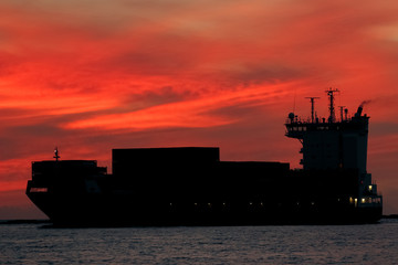 Large container ship silhouette arriving from Baltic sea at red