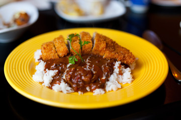 Tonkatsu curry on rice served on a yellow plate